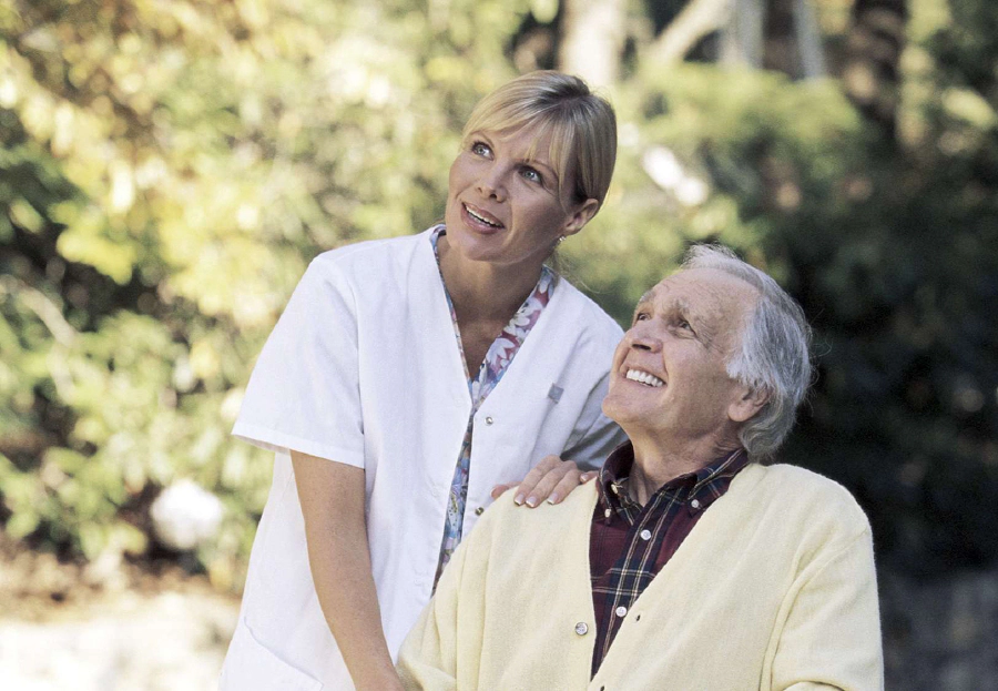 Homme âgé et infirmière à l'extérieur senior assis avec infirmiere regard vers l'horizon
