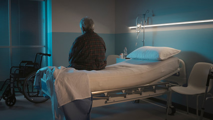 homme âgé assis de dos sur un lit d’hôpital