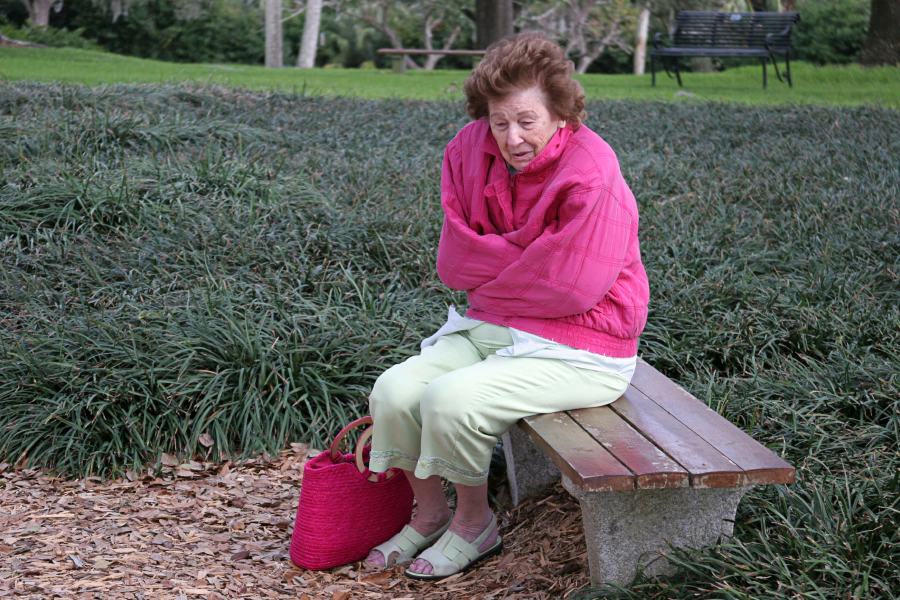 femme a froid assise sur un banc