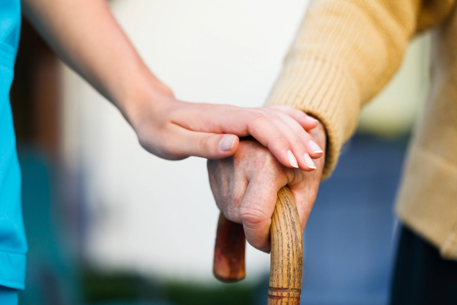Aide personne âgée avec canne personne en canne est aidée par une aide soignante
